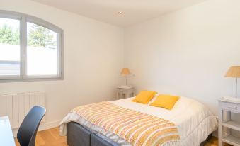 a white bedroom with hardwood floors , a bed , and a chair near the window , providing a comfortable and inviting atmosphere at Dade