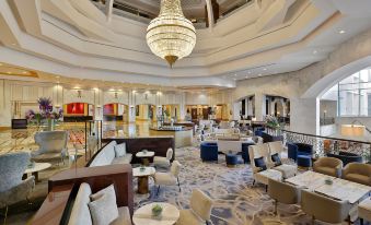a luxurious hotel lobby with high ceilings , a large chandelier hanging from the ceiling , and comfortable seating arrangements at The Ritz-Carlton, Doha