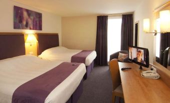 a hotel room with two beds , a desk , and a window , giving a comfortable and well - lit atmosphere at Dublin Airport