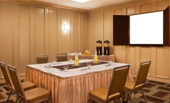 a conference room with a table set up for a meeting , featuring a large screen on the wall at Four Points by Sheraton Saginaw