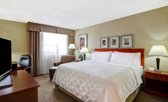 a large bed with white linens and a red headboard is in a hotel room at Holiday Inn Laval - Montreal