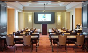 a conference room with multiple rows of chairs arranged in a semicircle , facing a projector screen at Hyatt Place Denver Cherry Creek