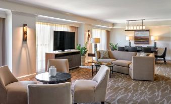 a modern living room with a large flat - screen tv mounted on the wall , surrounded by comfortable seating and dining areas at JW Marriott San Antonio Hill Country Resort & Spa