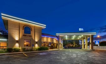 an exterior view of a best western hotel at night , with its lights illuminating the parking lot at Best Western Dunmar Inn