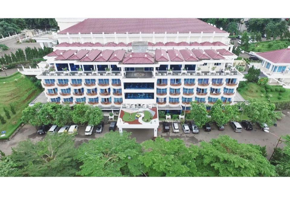 aerial view of a large white building with a red roof , surrounded by trees and cars parked in the lot at Braja Mustika Hotel Bogor