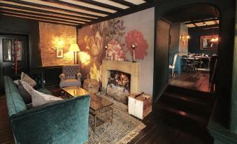 a cozy living room with a fireplace , wooden floors , and a dining area in the background at The Bull Hotel