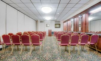 a conference room with rows of red chairs arranged in a semicircle , and a podium at the front at Ramada by Wyndham Metairie New Orleans Airport