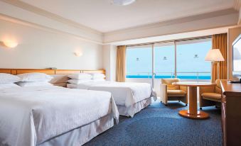 a hotel room with two beds , a desk , and a window overlooking the ocean , under a carpeted floor at Sheraton Grande Tokyo Bay Hotel