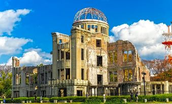 a large , old building with a dome on top and people walking in front of it at Hotel Hokke Club Hiroshima