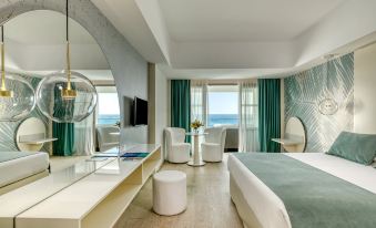 a modern hotel room with a view of the ocean , featuring a bed , dining table , and chairs at The Ivi Mare - Designed for Adults by Louis Hotels