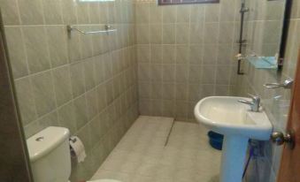a small , tiled bathroom with white walls and floor , a toilet , sink , and shower at Rivers Edge