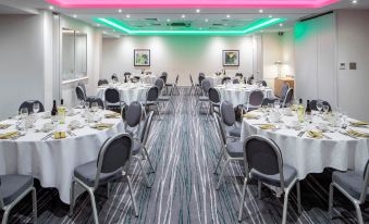 a well - lit dining room with tables and chairs arranged for a group of people to enjoy a meal at Holiday Inn Aylesbury