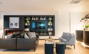 a modern living room with a large flat screen tv mounted on the wall , surrounded by various pieces of furniture such as couches and chairs at Gr8 Hotel Sevenum
