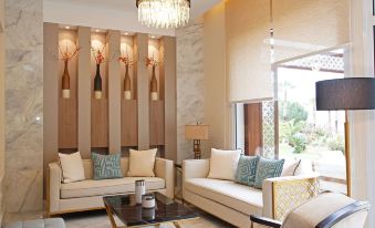 a luxurious living room with white couches and chairs , a coffee table , and a chandelier at Hotel Corsica & Spa Serena