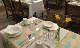 a dining room with a table set for breakfast , complete with plates , cups , and utensils at The Ardingly Inn