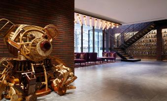 a lobby with a large clock in the center and a staircase leading up to it at Mitsui Garden Hotel Sapporo West
