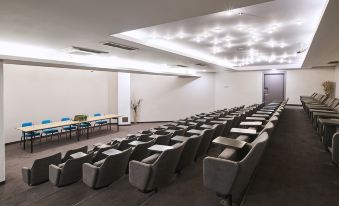 a large conference room with rows of gray chairs arranged in a semicircle , and a podium at the front of the room at Aminess Lume Hotel