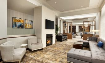 a modern hotel lobby with comfortable seating , a fireplace , and a large tv on the wall at DoubleTree by Hilton Hartford - Bradley Airport