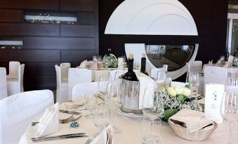 a table is set with white linens , silverware , and wine glasses in front of a black and white wall at Hotel la Lucertola