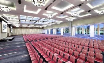 a large conference room with rows of red chairs arranged in a semicircle , and a podium at the front of the room at Racv Royal Pines Resort Gold Coast