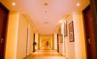 a long hallway with yellow walls and a yellow ceiling , featuring framed pictures on the walls at Palm Seremban Hotel