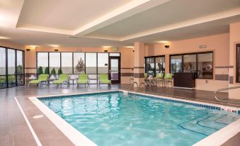 a large indoor swimming pool with a blue water and green lounge chairs surrounding it at Courtyard Cleveland Elyria