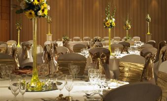 a well - decorated banquet hall with multiple tables set up for a formal event , including gold chairs and white tablecloths at London Heathrow Marriott Hotel
