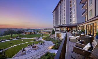 a large hotel with a beautiful outdoor seating area and a golf course in the background at Omni Barton Creek Resort and Spa Austin