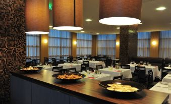 a restaurant with a long dining table and chairs , as well as several bowls of food on the table at Axis Porto Business & Spa Hotel