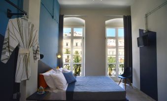 a bedroom with a large bed and a view of the city through two windows at Habit
