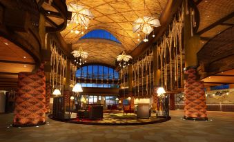 The lobby and ceiling of a spacious building are illuminated by overhead lighting at Disney Explorers Lodge