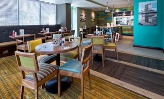 a modern cafe with wooden tables , chairs , and a bar , decorated in various colors and patterns at Premier Inn Oban