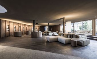 a large , modern living room with wooden floors and white couches arranged around a coffee table at Adler Spa Resort Dolomiti