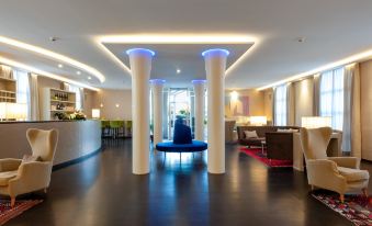 a modern hotel lobby with high ceilings , wooden floors , and columns , as well as various seating areas at Hotel San Marco