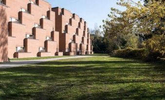 a large building with multiple levels of windows is surrounded by a grassy area and trees at FlyOn Hotel & Conference Center