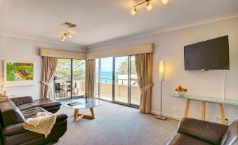 a modern living room with a large window and sliding glass door leading to an ocean view balcony at Aurora Ozone Hotel Kangaroo Island