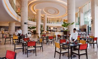 a large , well - lit hotel lobby with multiple dining tables and chairs arranged for guests to enjoy a meal at Courtyard by Marriott Mumbai International Airport
