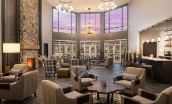 a large hotel lobby with high ceilings , high windows , and various seating arrangements for guests at Saranac Waterfront Lodge, Trademark Collection by Wyndham