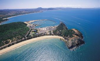 an aerial view of a small island surrounded by the ocean , with a sandy beach in the foreground at Rosslyn Bay Resort