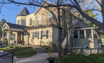 a large , two - story house with a beige exterior and black roof , surrounded by lush greenery at Inn at the Falls