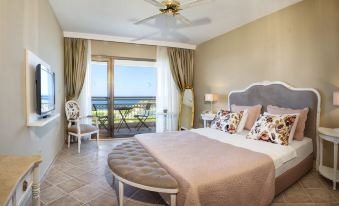 a spacious bedroom with a king - sized bed , a ceiling fan , and a balcony overlooking the ocean at Hotel Carina