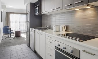 a modern kitchen with white cabinets and stainless steel appliances , including a stove and microwave at Quest Werribee