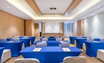 A spacious event room is arranged with blue and white chairs on the headrests at Holiday Inn Express Shanghai Zhenping