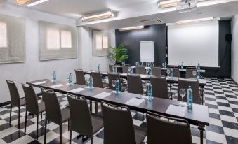 a conference room set up for a meeting , with chairs arranged in rows and a whiteboard on the wall at Salles Hotel Aeroport de Girona