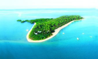 an aerial view of a small island surrounded by water with boats in the distance at Likuri Island Resort Fiji