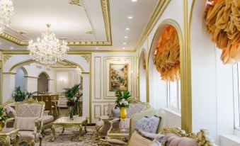 a luxurious living room with white walls , gold trim , and a chandelier , decorated with furniture and plants at Mangrove Hotel