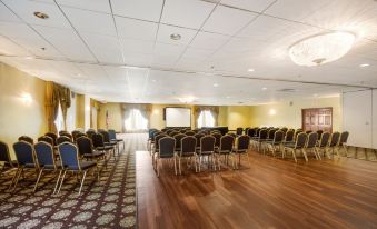 a large , empty conference room with rows of chairs and a projector screen at the front at Chester Hotel and Conference Center
