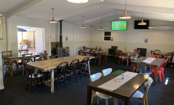 a large dining room with multiple tables and chairs , a television mounted on the wall , and a fireplace at Warrego Hotel Motel Cunnamulla