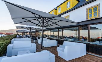 a rooftop patio with several white lounge chairs and umbrellas , providing shade and seating for guests at Luna Hotel Serra da Estrela