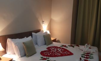 a hotel room with a king - sized bed adorned with rose petals , creating a romantic atmosphere at The Esquire